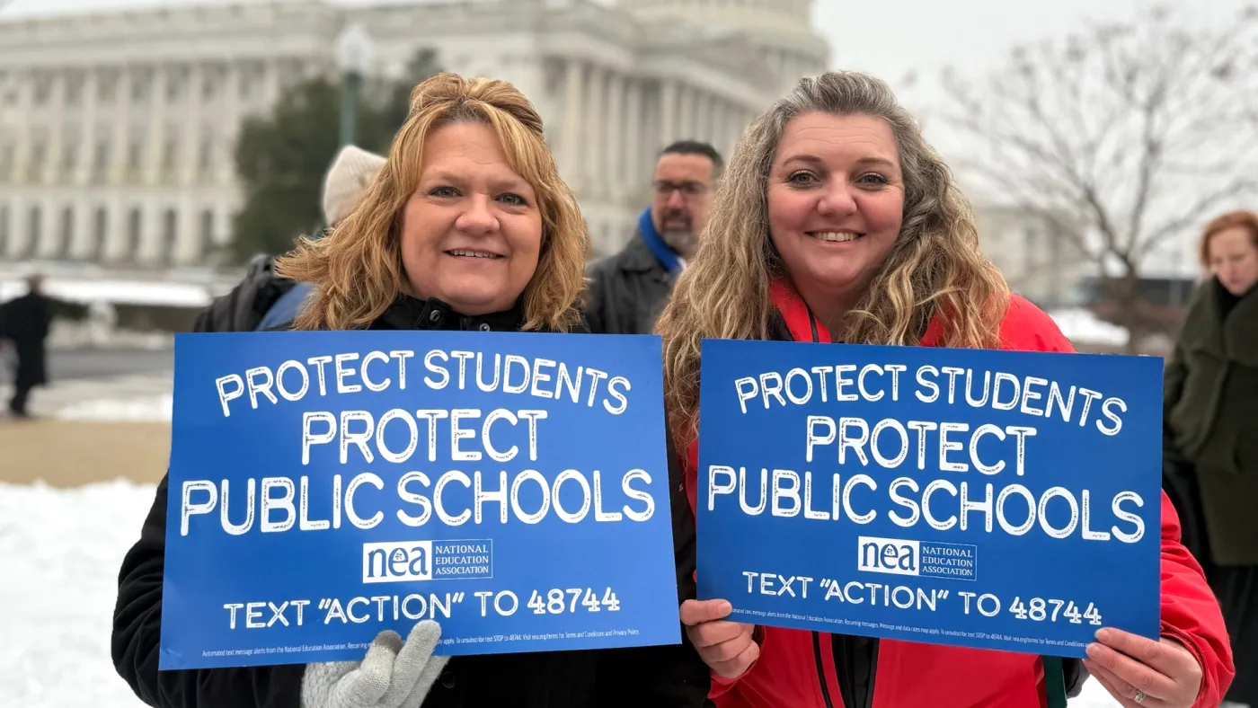 WEA President and NEA Representative holding signs to Protect Public Schools
