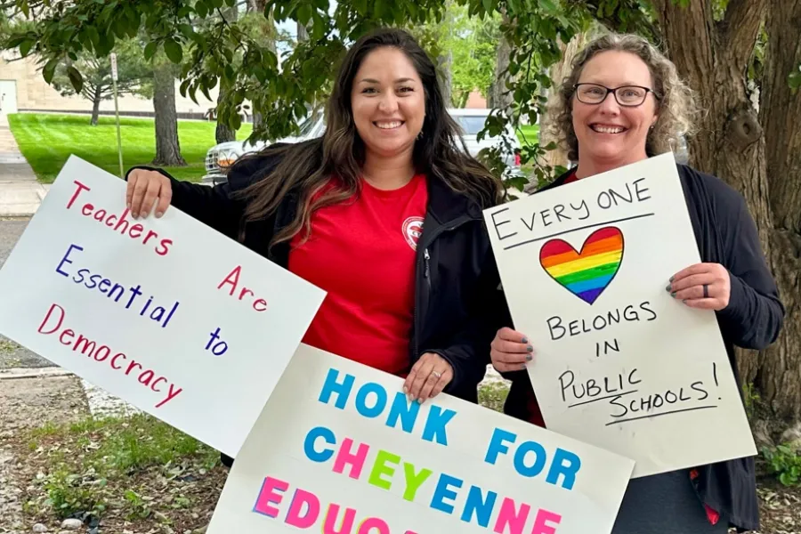 Two WEA members smile with supportive signs for students